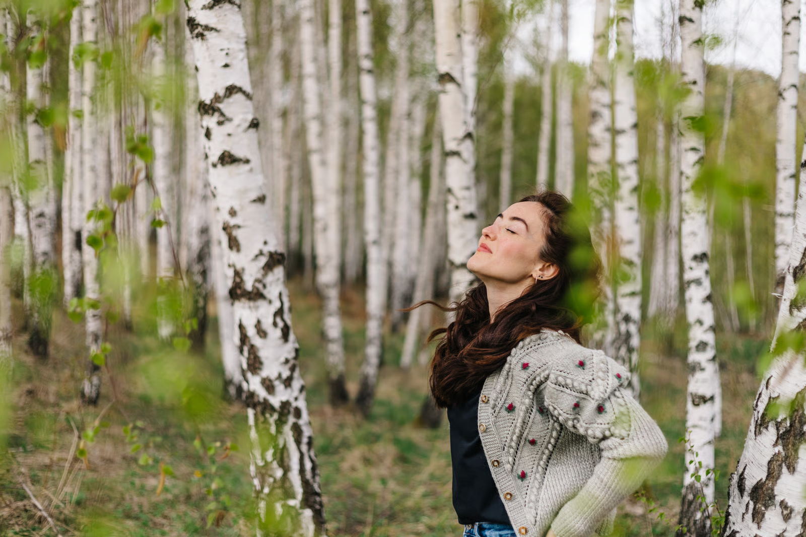 Woman being happy while being in nature, in a forest with birch trees_