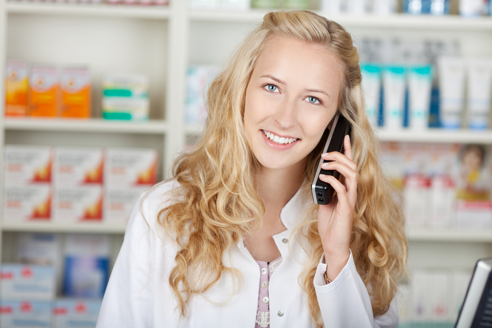 Portrait of happy female pharmacist communicating on cordless phone in pharmacy