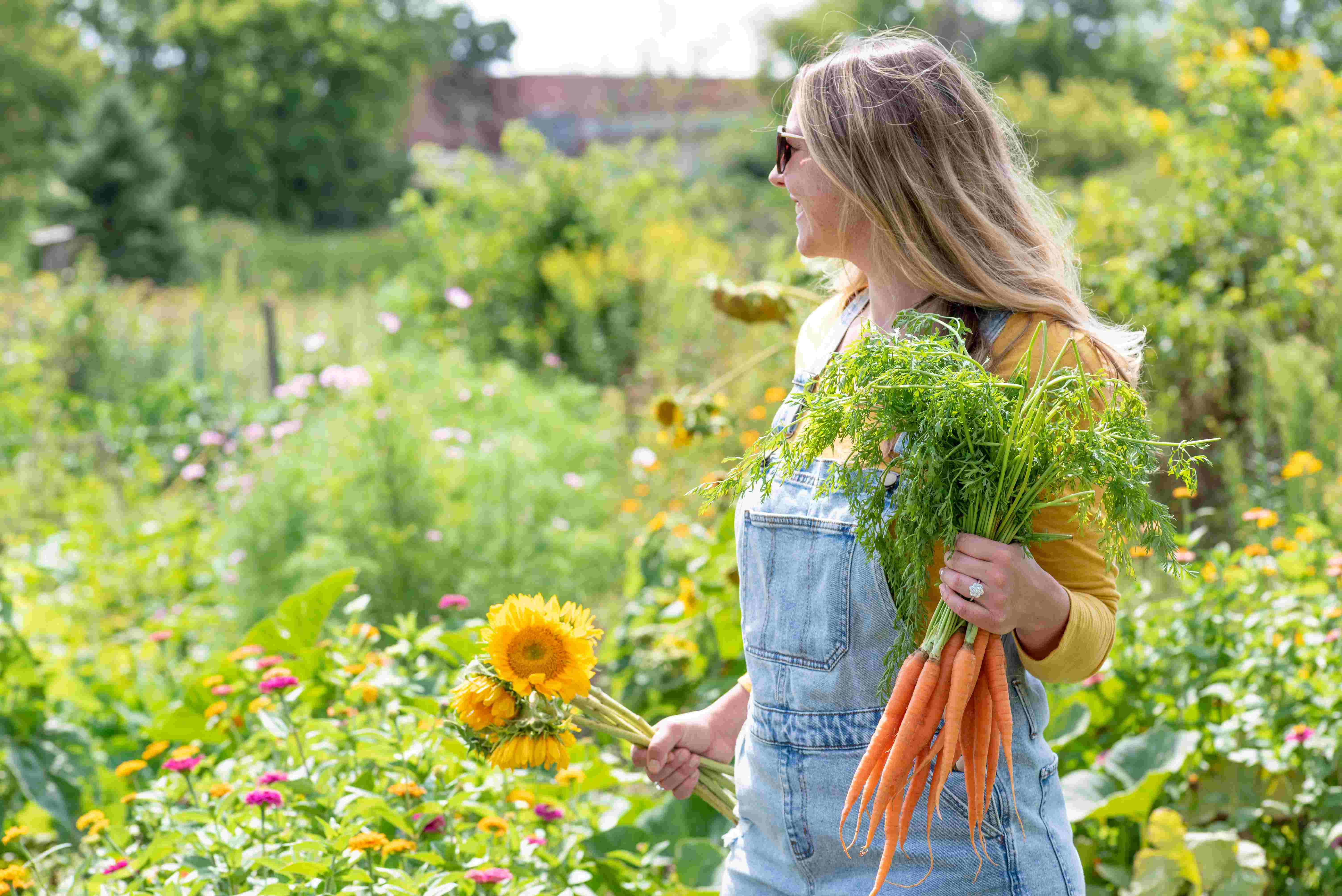 Frau in bunten Garten mit Karotten in der Hand