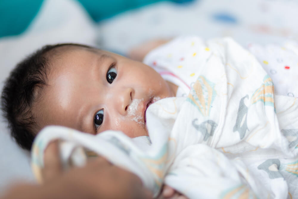 Baby schaut mit grossen Augen und verschmiertem Mund in die Kamera